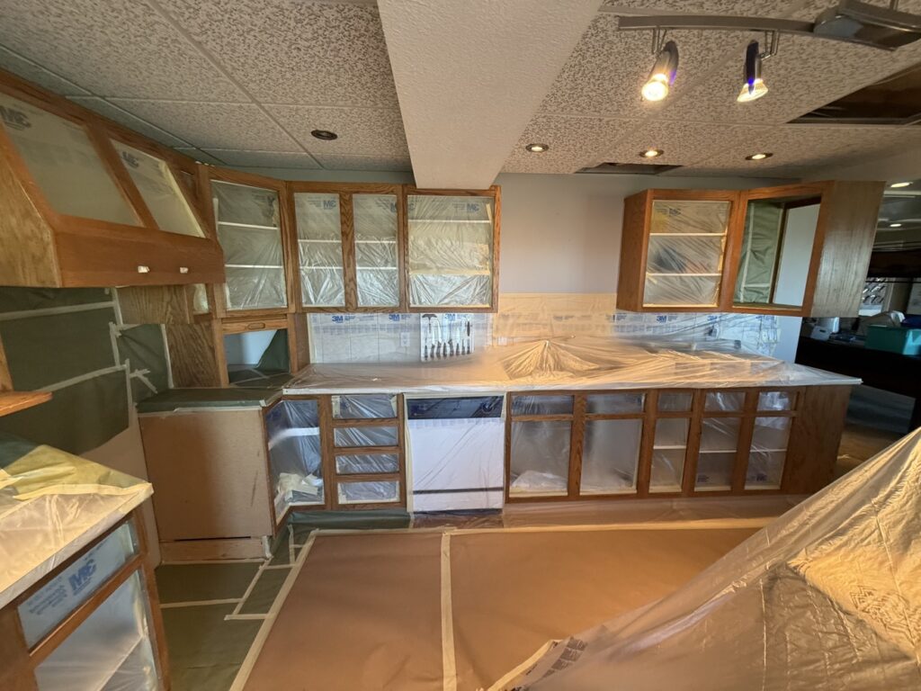 Cabinet painting preparation in a Calgary kitchen — cabinets masked and protected by Renovo Painting Inc