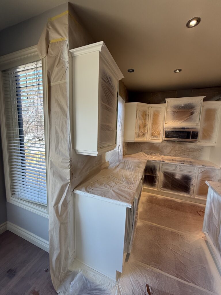 Kitchen cabinet frames being painted white in place by Renovo Painting Inc, Calgary