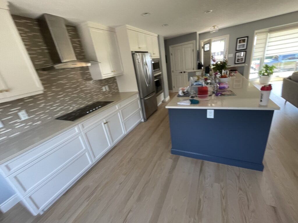 Kitchen after cabinet refinishing — white cabinets with navy island by Renovo Painting Inc, Calgary